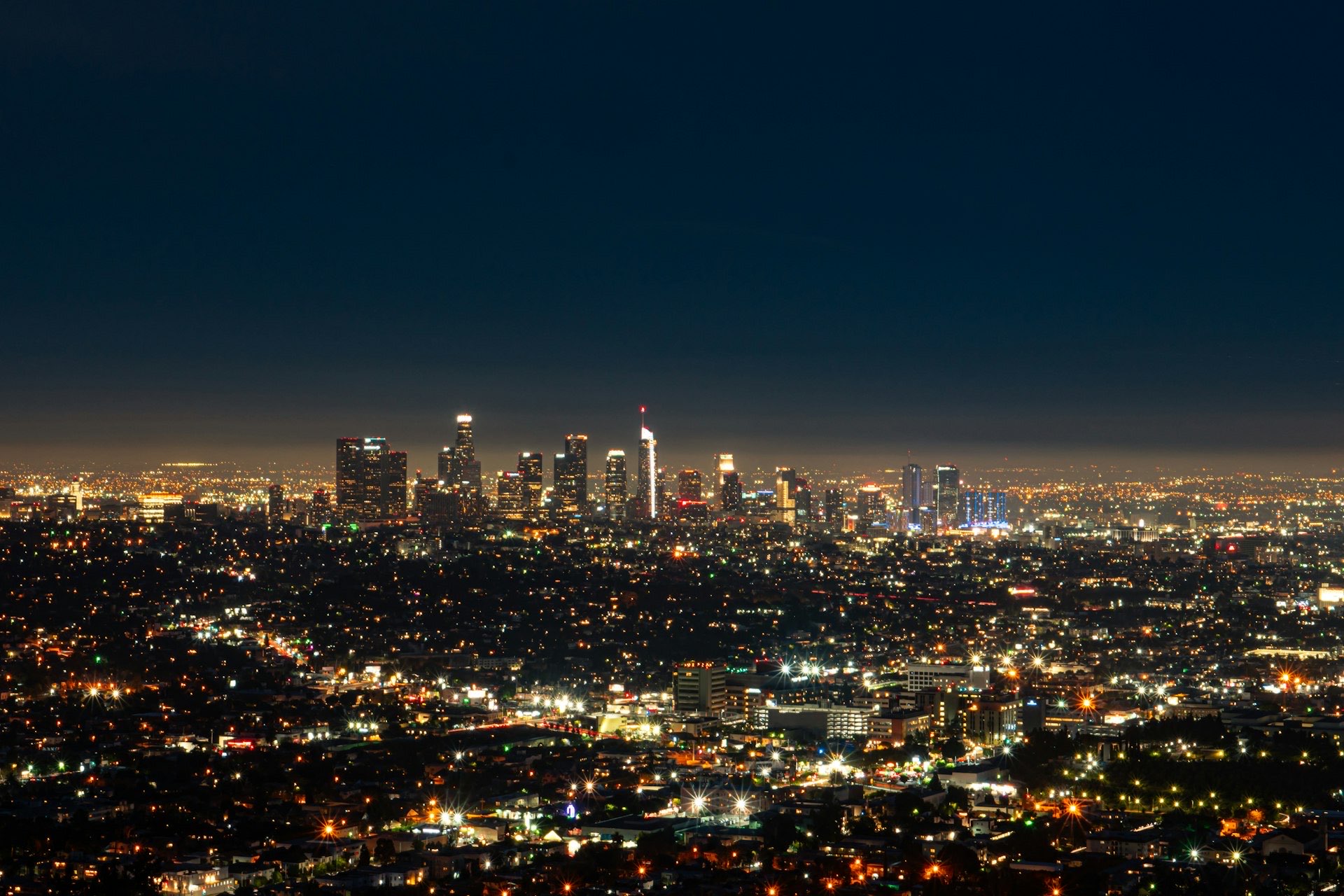 Downtown Los Angeles skyline at night above a sea of city lights