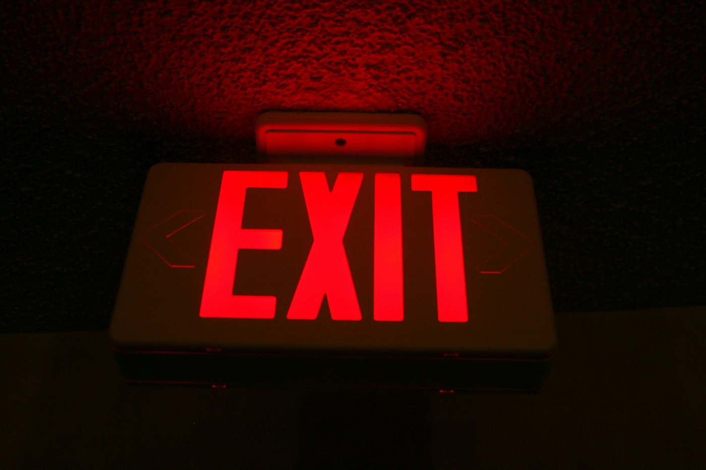 US-style red EXIT sign glowing in a dark room, red light spilling onto the ceiling