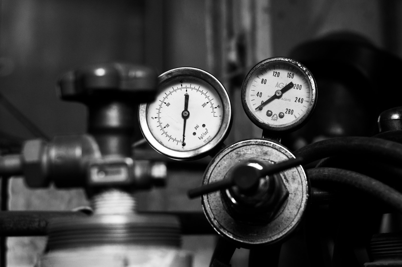 Black-and-white close-up of two analog pressure gauges on industrial valves
